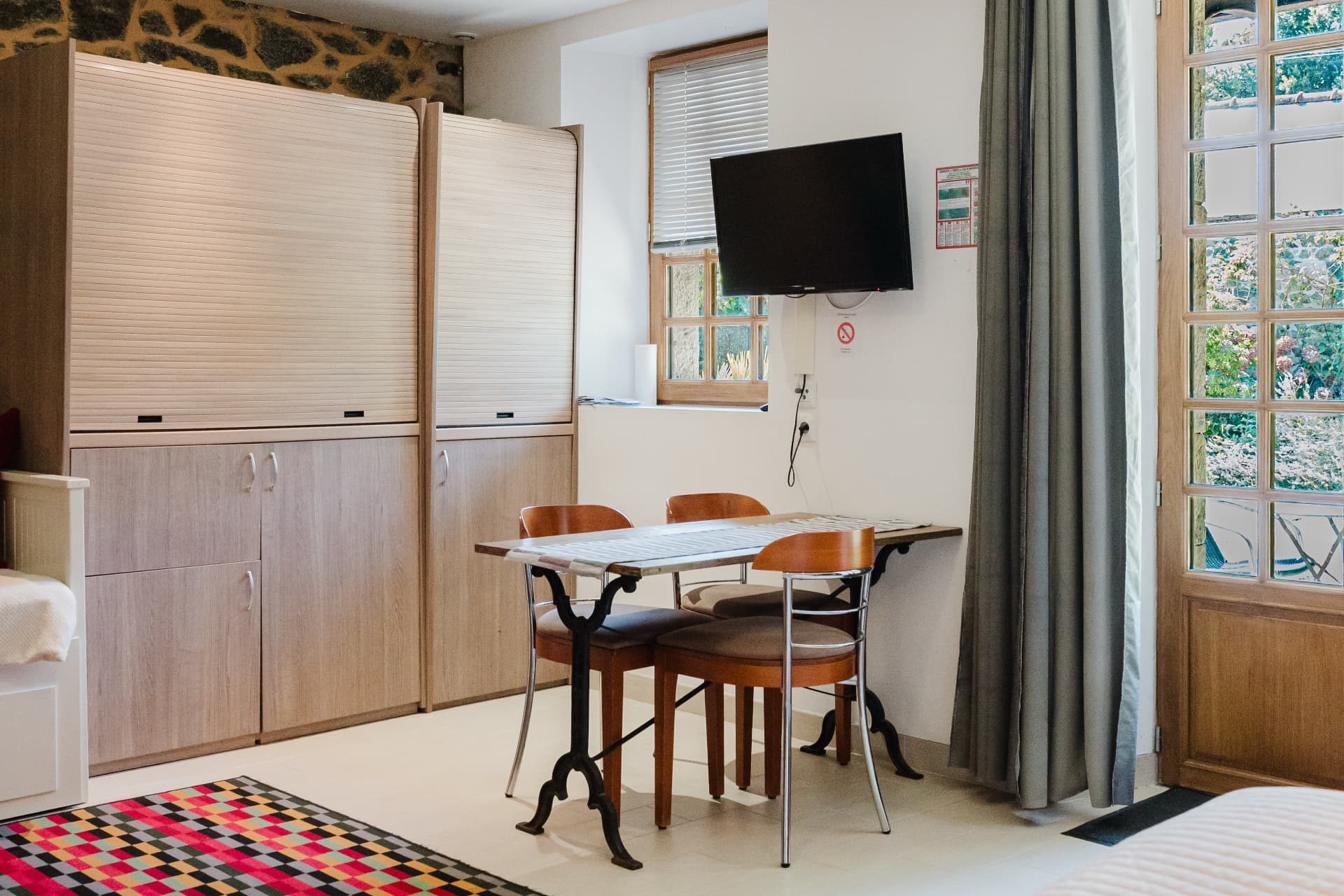 Coin repas avec table bistrot, chaises et télévision à écran plat
