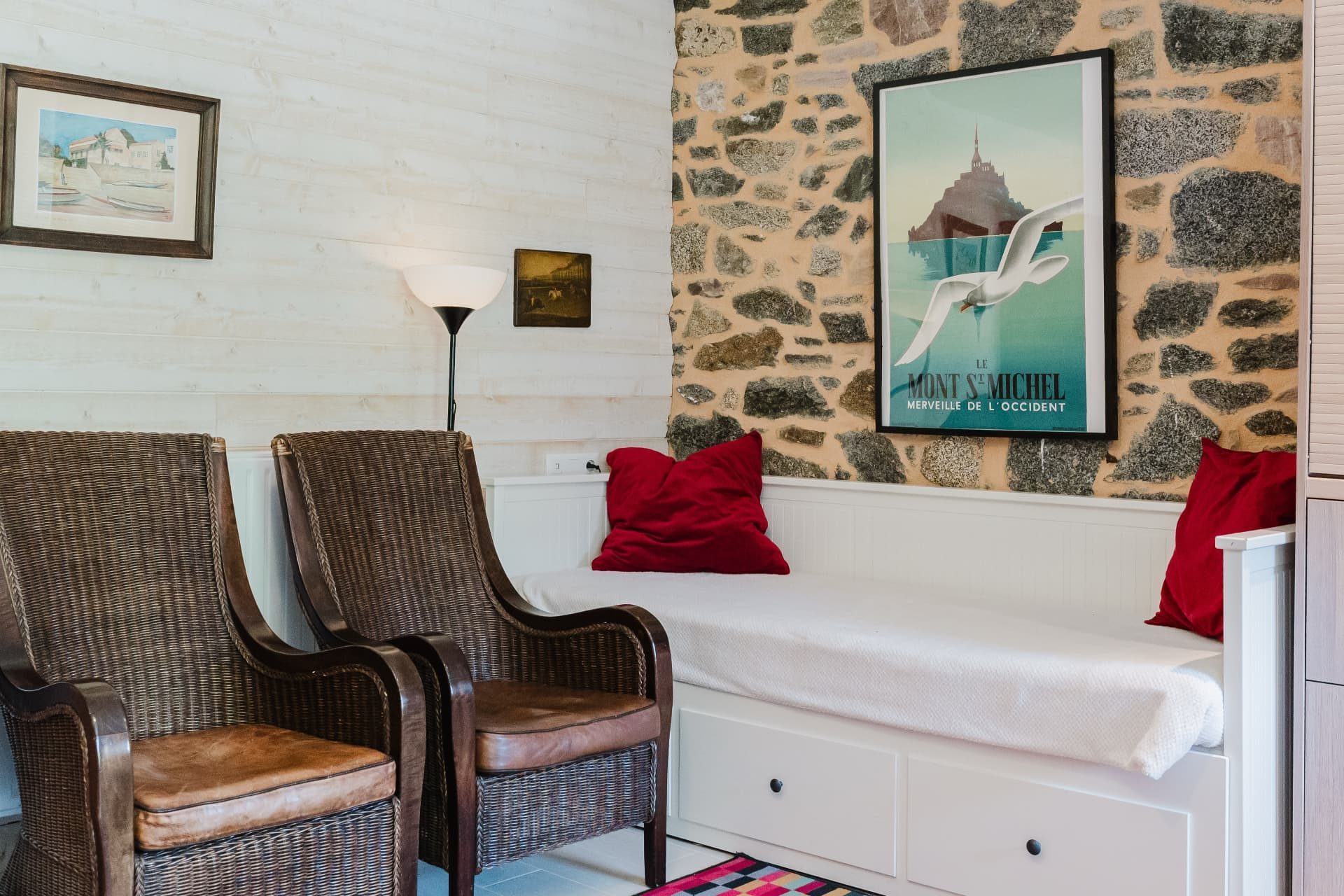 Coin salon avec fauteuils en rotin et banquette près du mur de pierre
