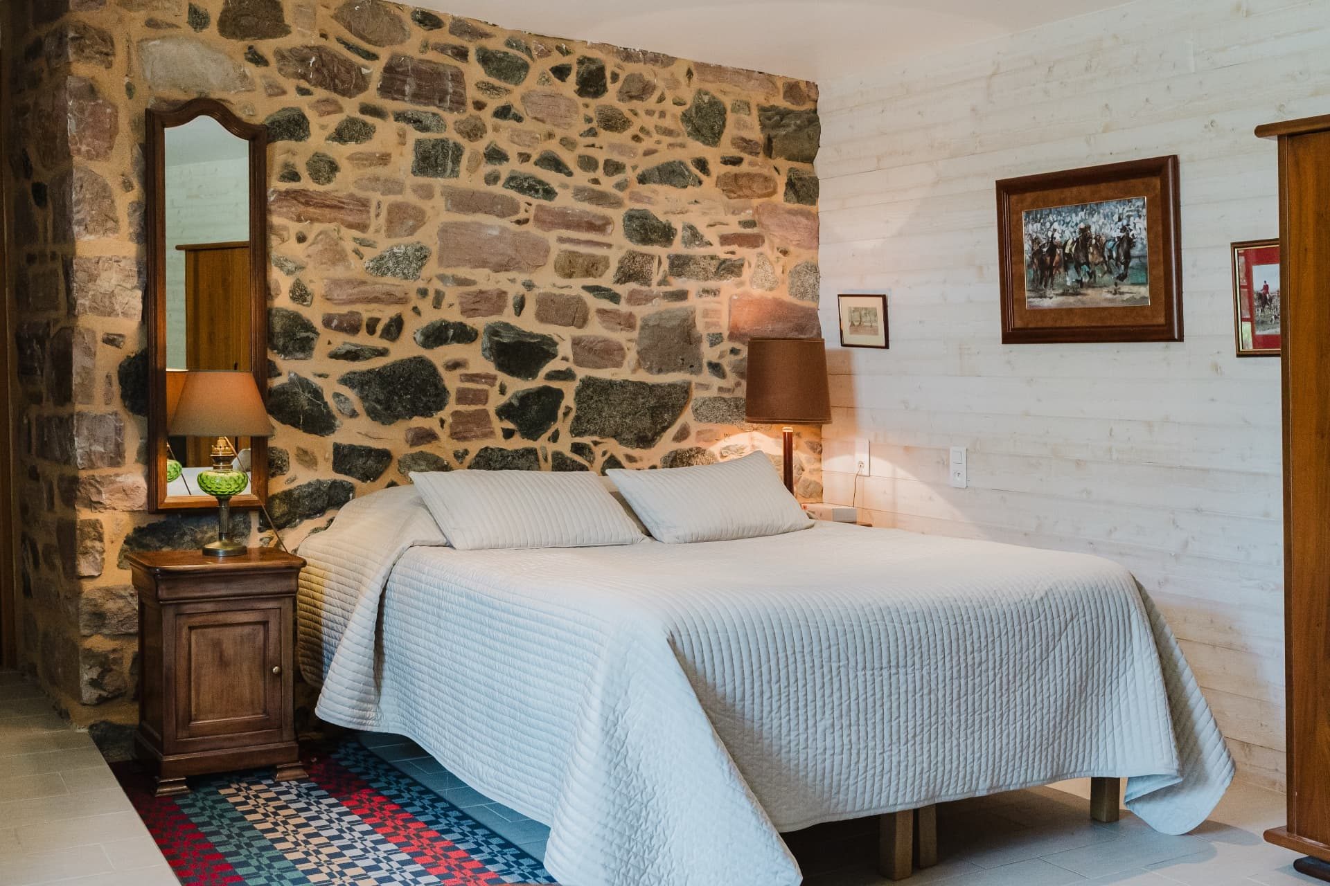 Lit double devant un mur de pierre apparente dans la chambre avec kitchenette
