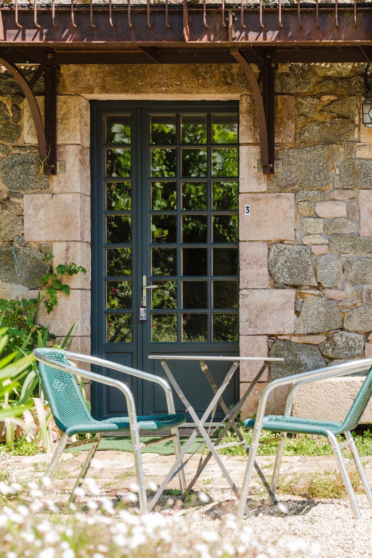 Terrasse privative avec table et chaises devant la façade en pierre